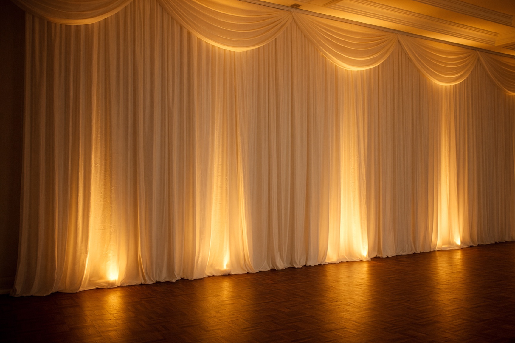 Champagne uplighting on draped ballroom walls in Orlando